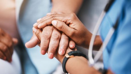 A nurse is holding hands with a patient