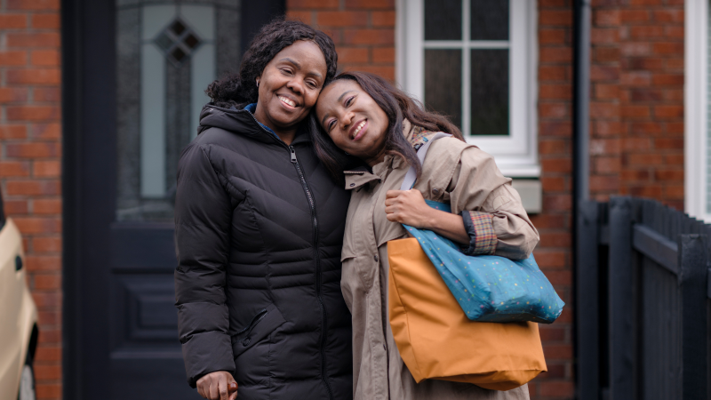 A carer and her mother share a hug outside the house